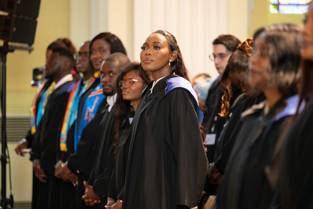 A graduate stands among her peers during the convocation ceremony.