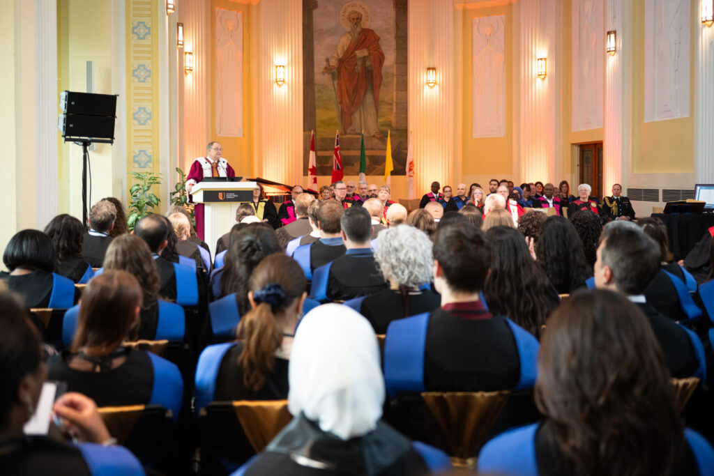 A bishop addresses graduates at the podium during the Saint Paul University convocation.