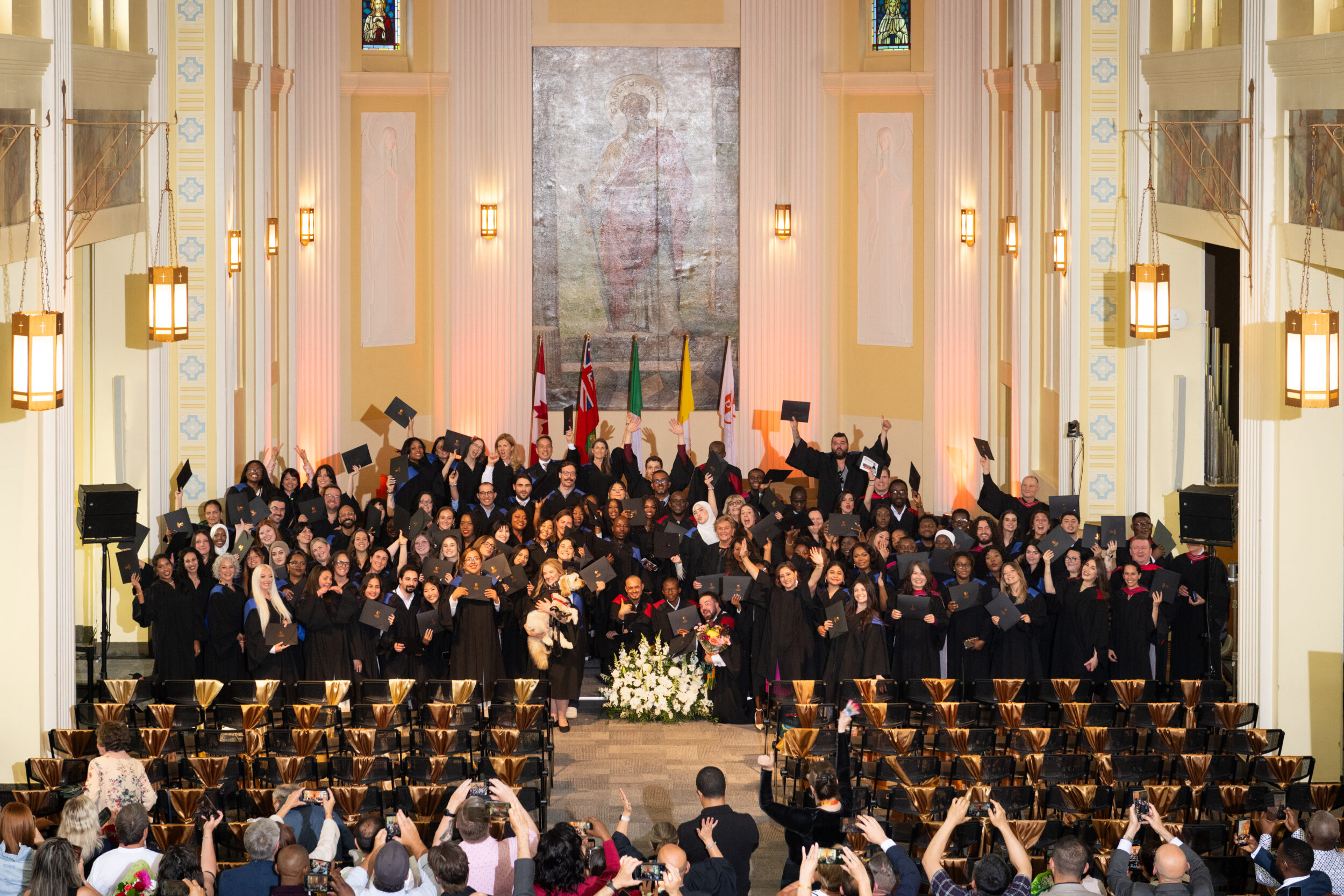 Afternoon ceremony graduates toss their caps in celebration in the De Mazenod Chapel.