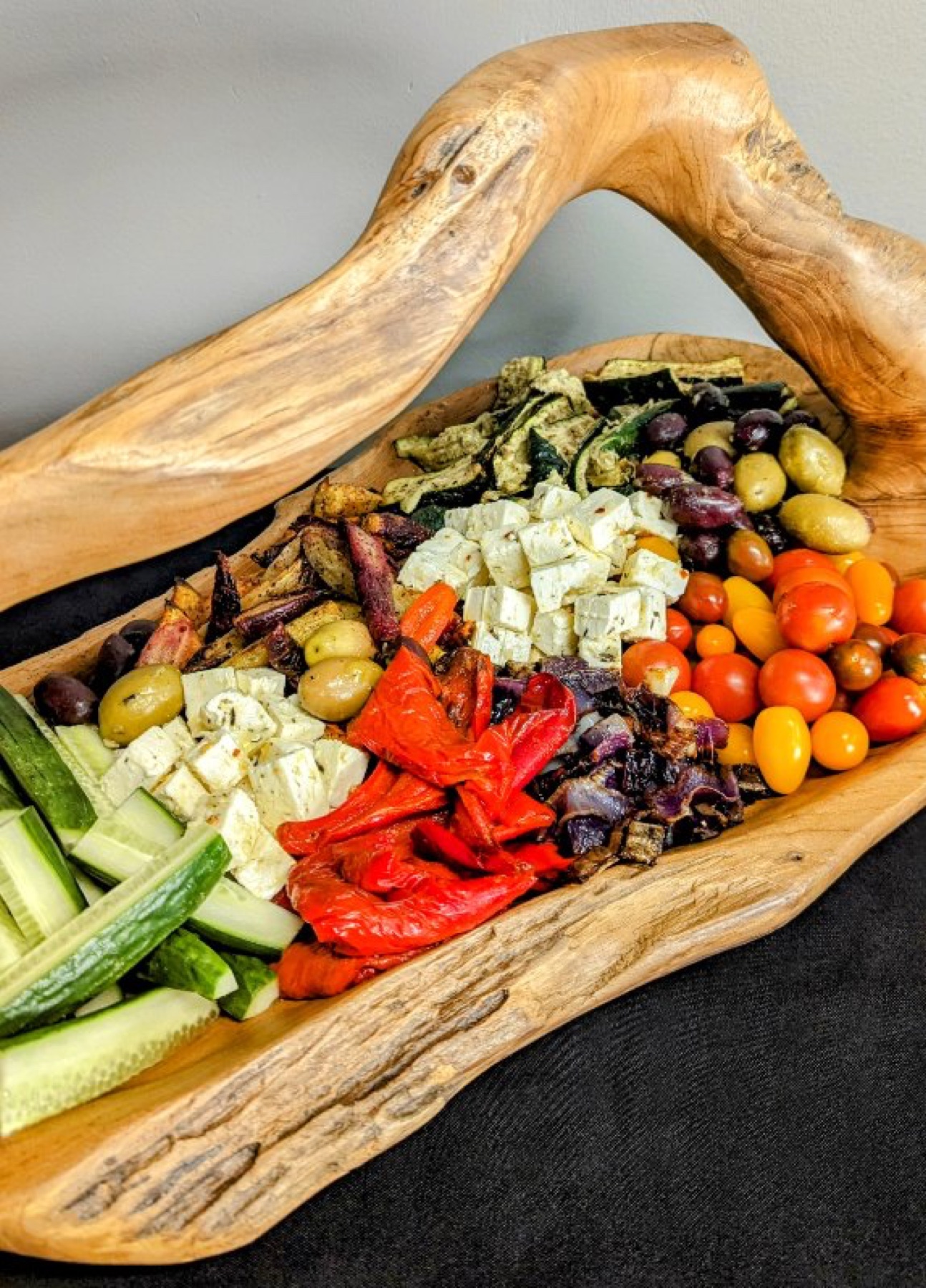 Platter of fresh vegetables, cheese and olives on a wooden board