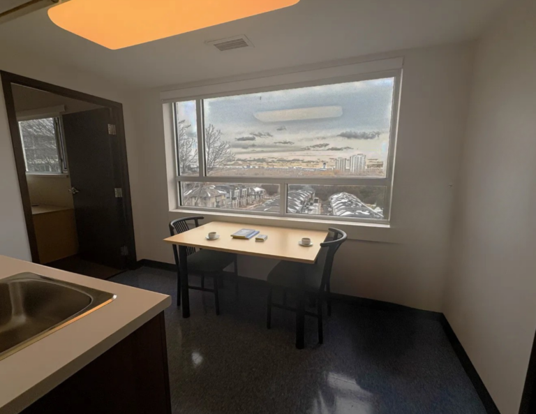 Suite dining table with two chairs in front of a large window overlooking the city