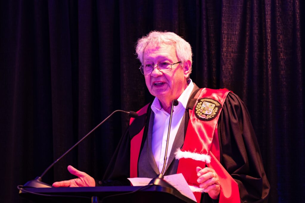 François Saillant, en toge avec une écharpe rouge, prend la parole au lutrin après avoir reçu son doctorat honorifique de l’Université Saint-Paul.