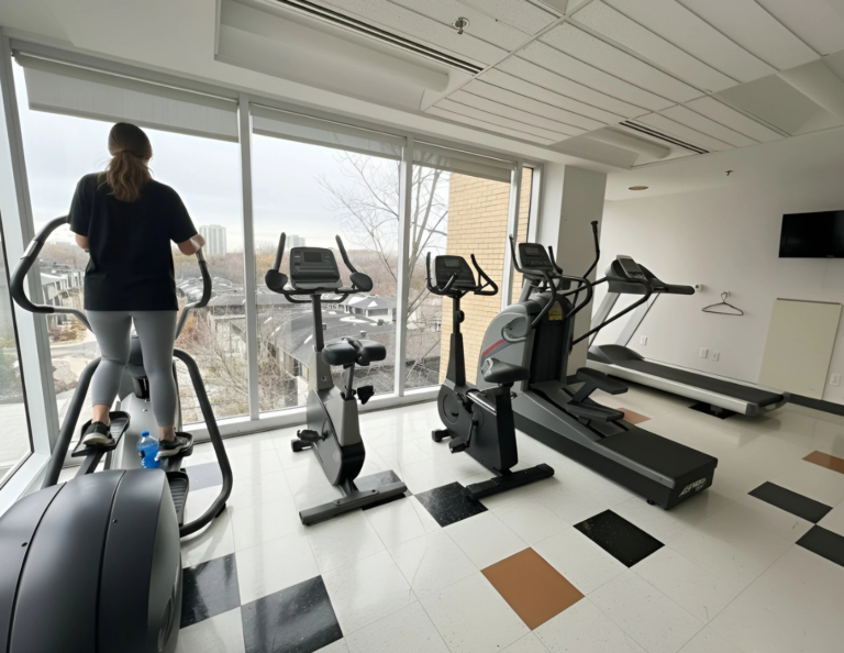 Residence fitness room with an elliptical, exercise bikes and a treadmill beside floor-to-ceiling windows